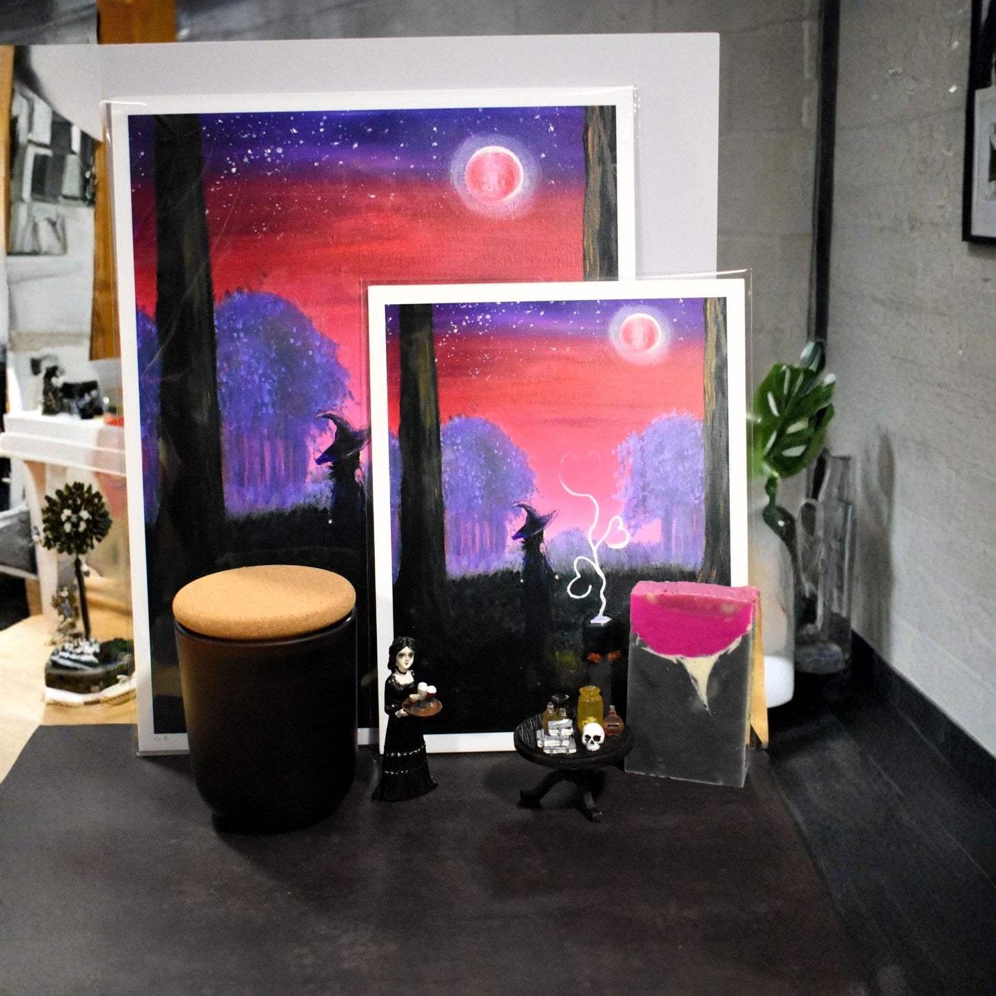 Two framed artworks on a table with a dark background
